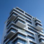 Striking low-angle shot of a modern condominium with unique balcony design and clear blue sky.